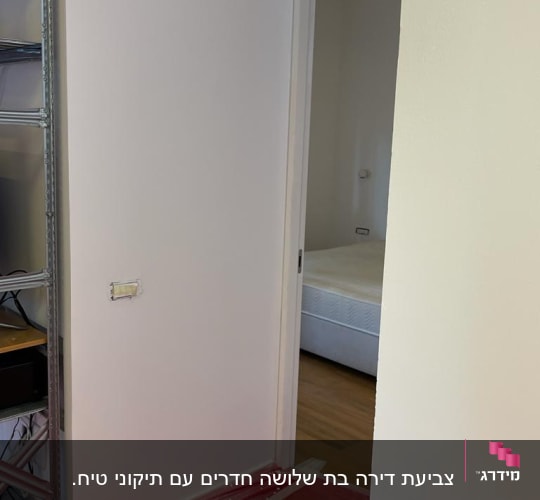 קיר צבוע בלבן עם יריעת פלסטיק אדומה על הרצפה